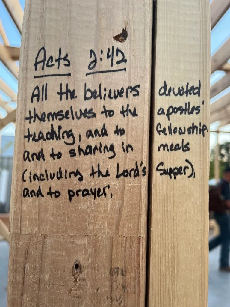 Acts 2:42 handwritten on a wooden stud of the new building